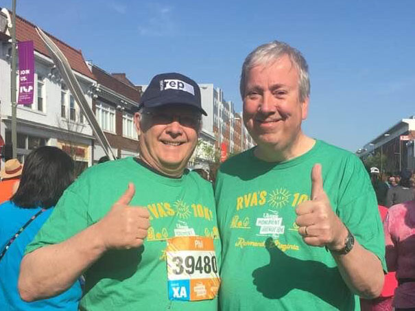Photo of two smiling men wearing green t-shirts at a 10K race giving the thumbs-up sign