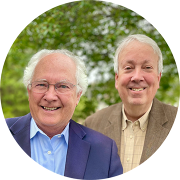 Photo of two smiling men in suits standing in front of trees